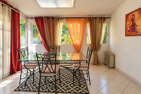 Salle à manger lumineuse, table en verre et jardin